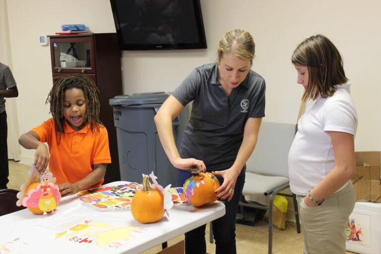 Woman painting a pumpkin with school kids