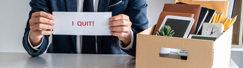 Man holding a sign saying "I quit" with box of office items
