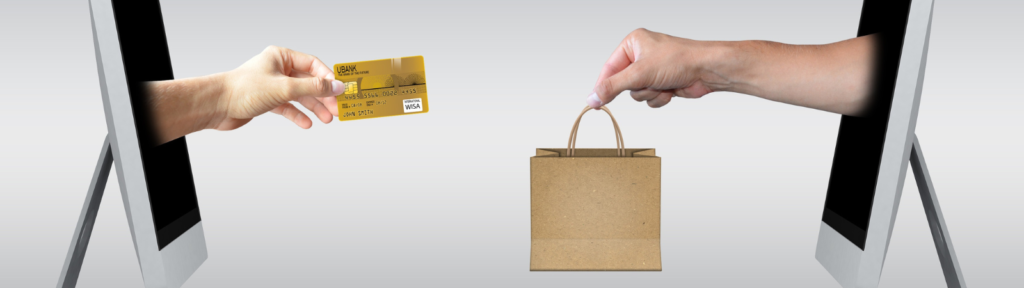 hand with credit card coming out of one computer and hand with shopping bag coming out of another computer