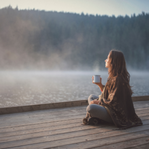 woman with coffee cup by lake