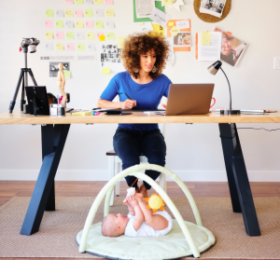 Woman working while a baby is laying under her desk