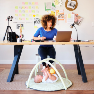 Woman working while a baby is laying under her desk